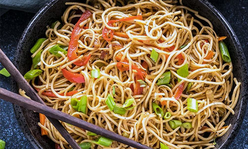 Deep bowl of hot vegetable hakka noodles with fresh cabbage